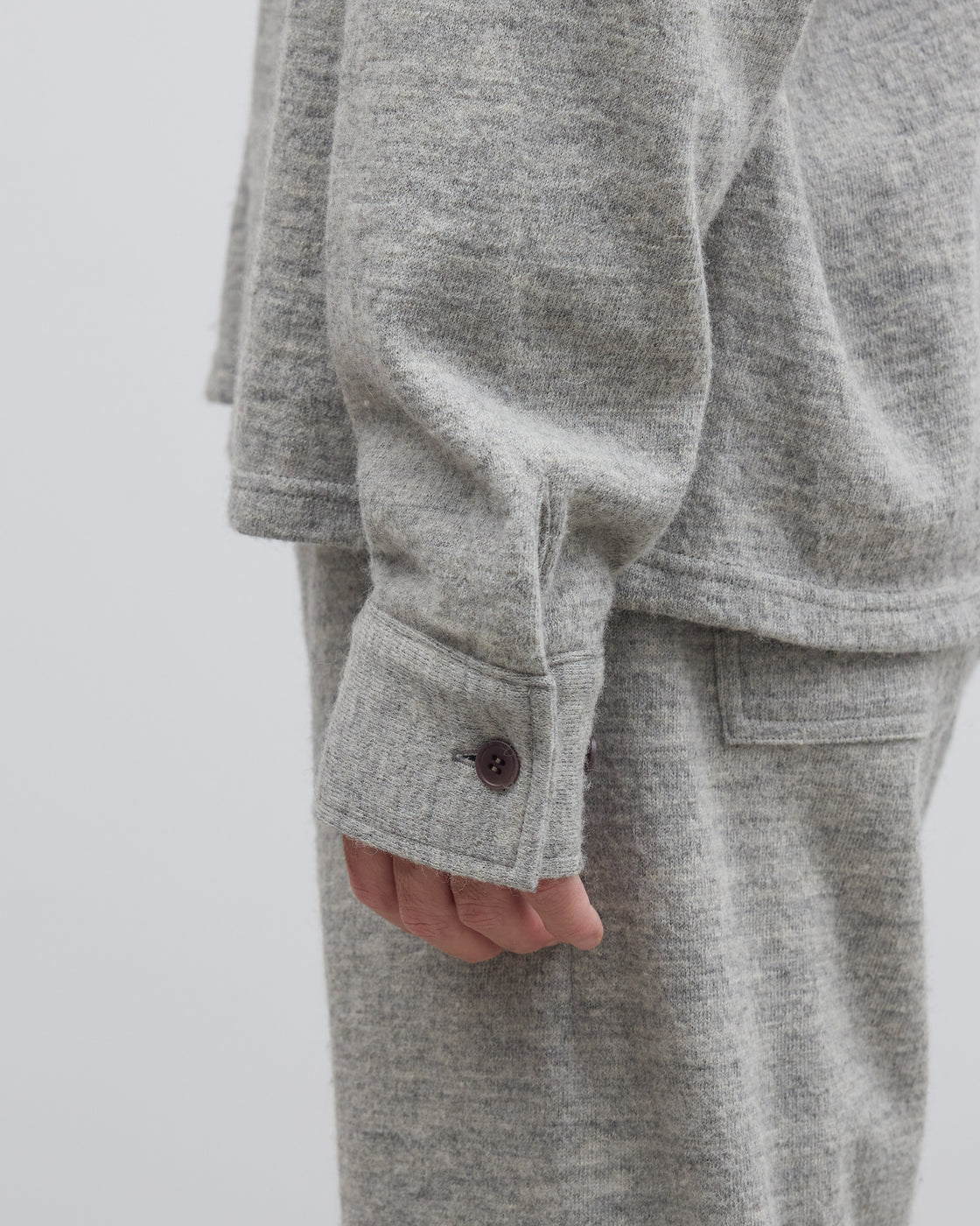 グレーのメランジ糸ハーフジップニットプルオーバーのクローズアップ、シェットランドウールとコットンの撚り合わせによる独特な表情とスウェットのようなリラックス感が特徴の日本製ニット