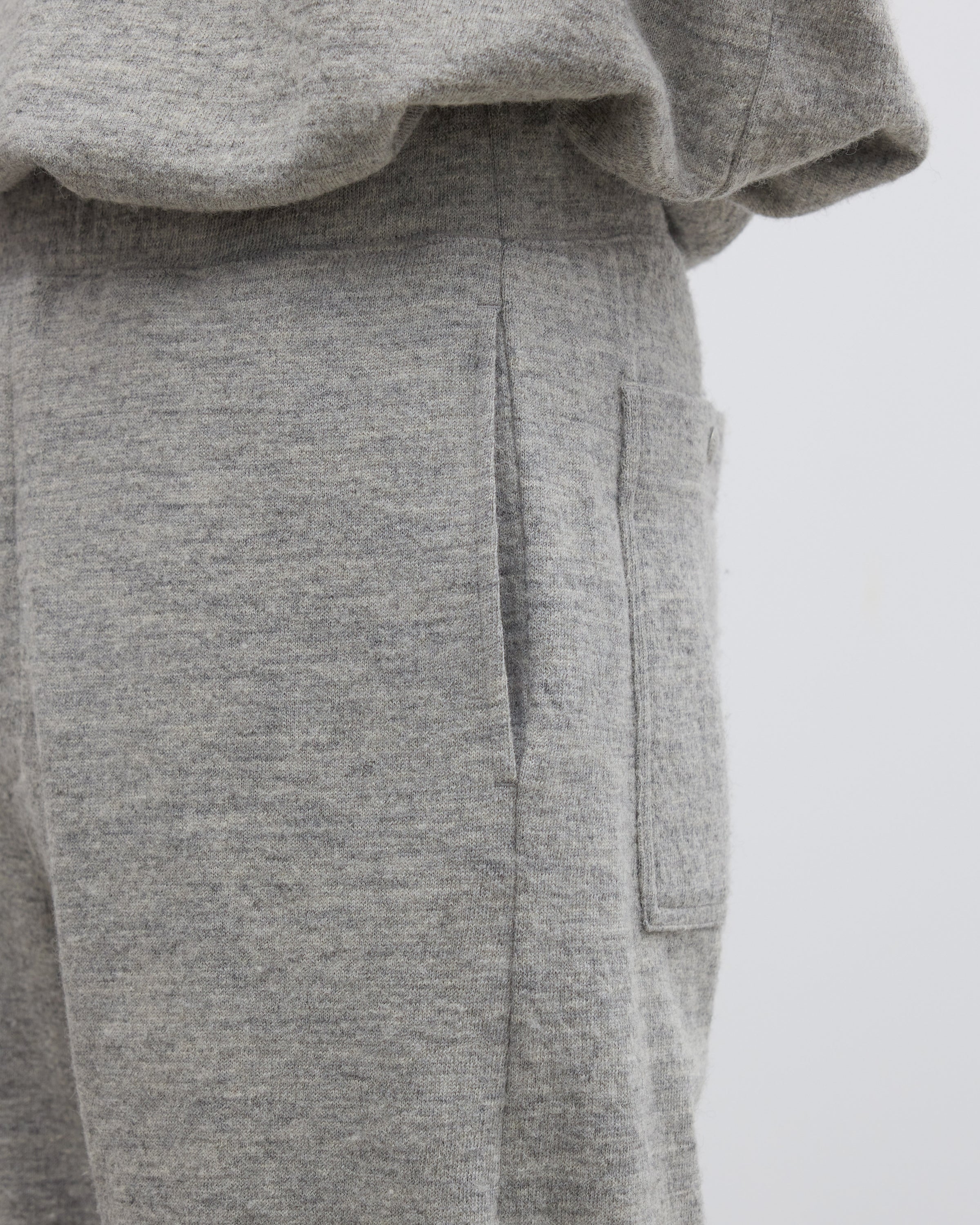 Keylime Tokyoのシェットランドウール混ニットパンツのストレートシルエットが際立つ着用シーン、杢調メランジ感と深めの股上が特徴的なグレーのイージーパンツ、尾州産素材