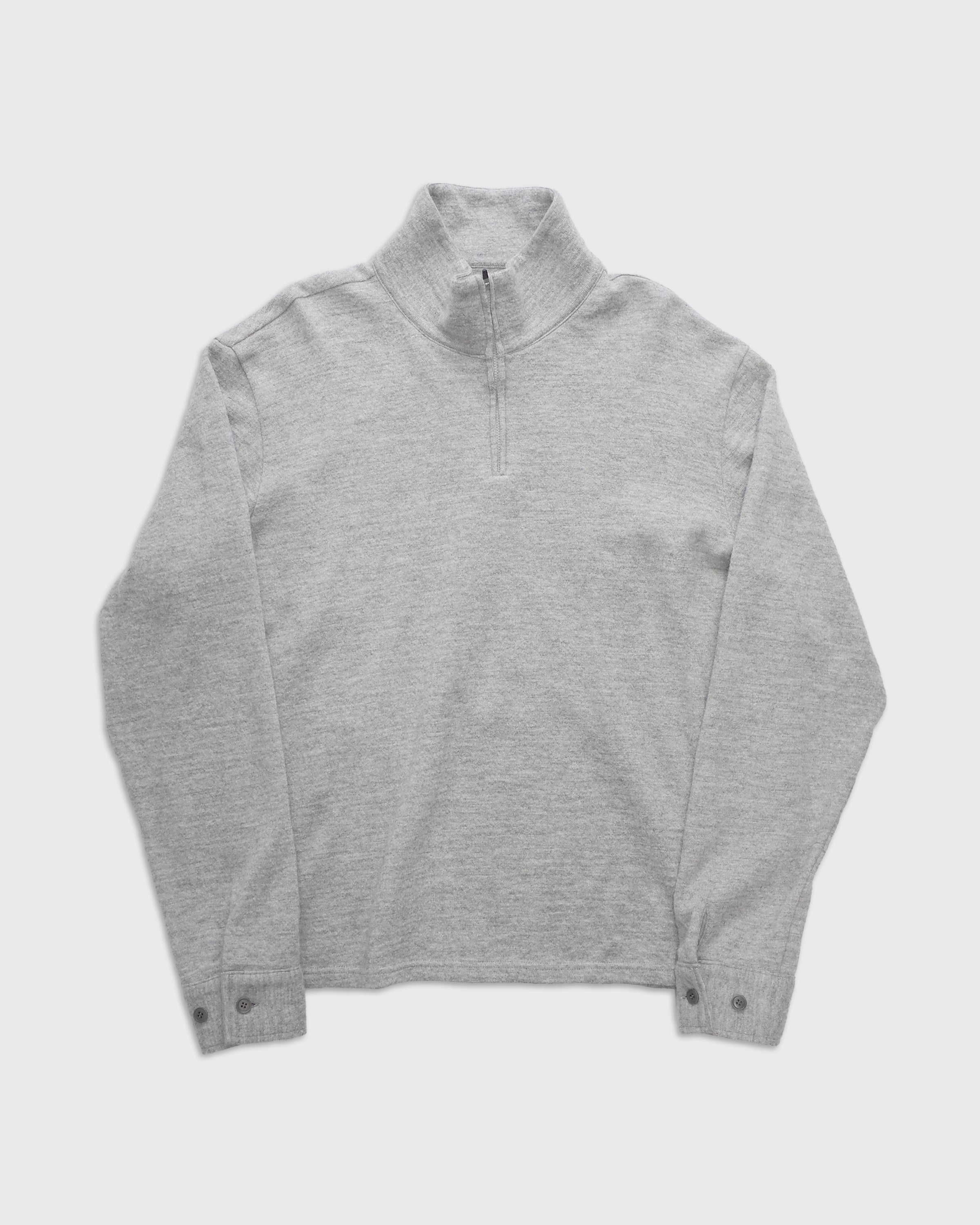 グレーのシェットランドウールとコットンを撚り合わせたメランジ糸のハーフジップニットプルオーバーを着用したモデルの全身正面写真、日本製の上質なニットウェアの質感と柔らかな風合いが伝わる一枚